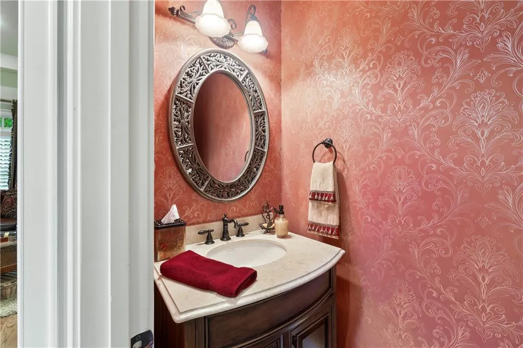 Half bath with wallpapered walls and vanity
