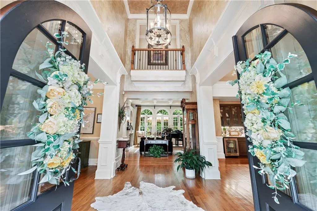 Foyer entrance featuring wood finished floors, decorative columns, beverage cooler, a chandelier, and a decorative wall