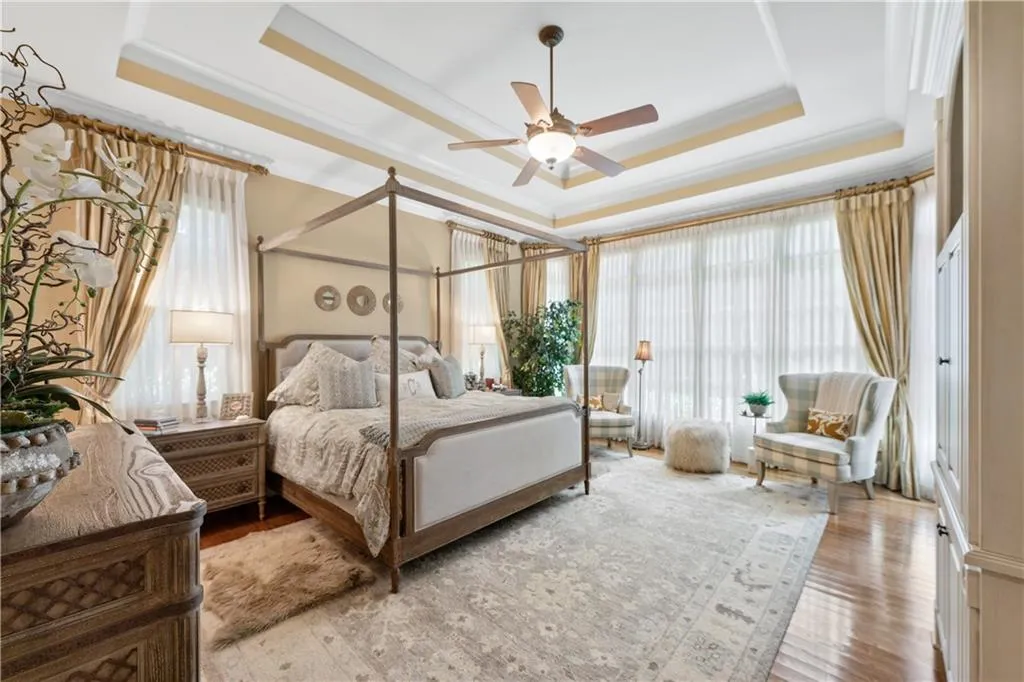 Bedroom with a tray ceiling, light wood-type flooring, ornamental molding, and ceiling fan