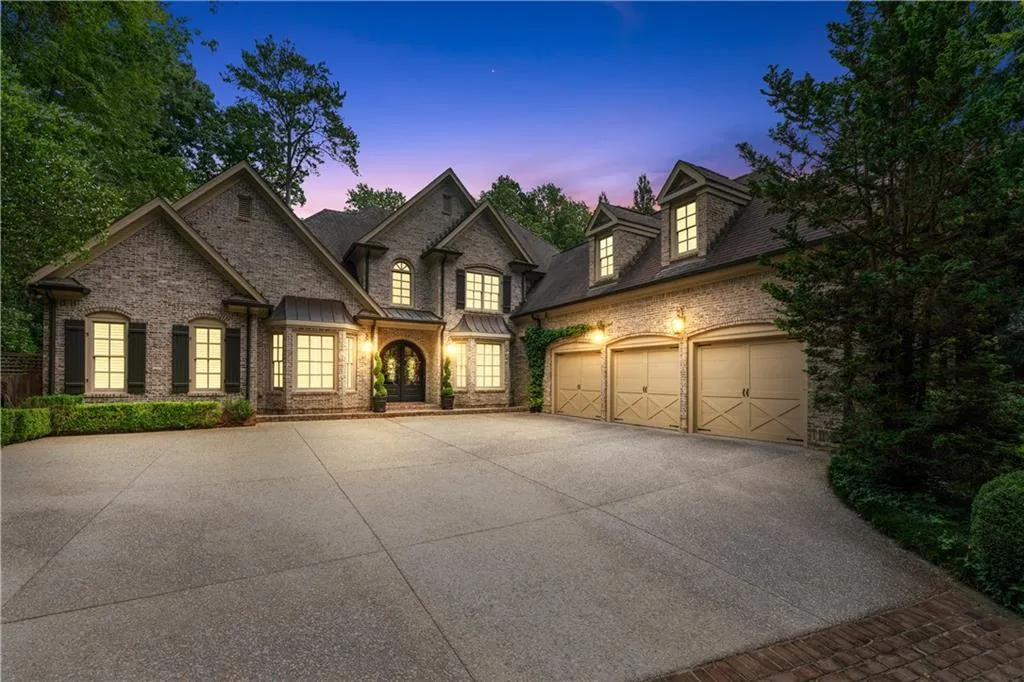 French country home featuring driveway, a garage, and brick siding