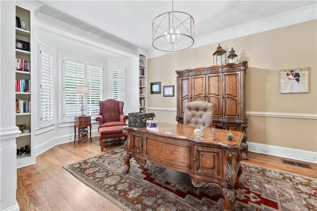 Office area with a chandelier, light wood-style floors, crown molding, and built in features