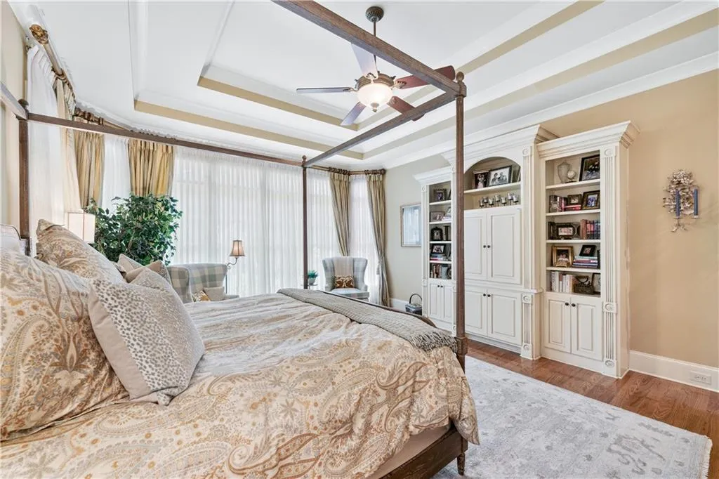 Bedroom featuring a tray ceiling, wood finished floors, ornamental molding, and ceiling fan