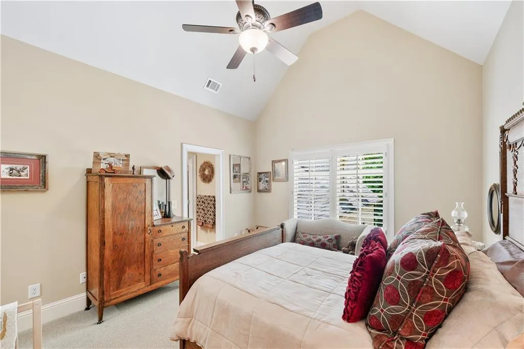 Bedroom featuring high vaulted ceiling, light carpet, and a ceiling fan