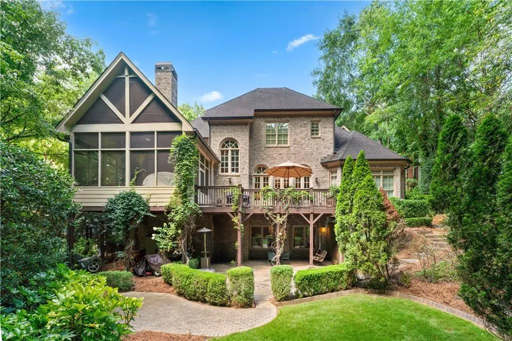 Back of house featuring a wooden deck, a chimney, a patio, a sunroom, and a yard