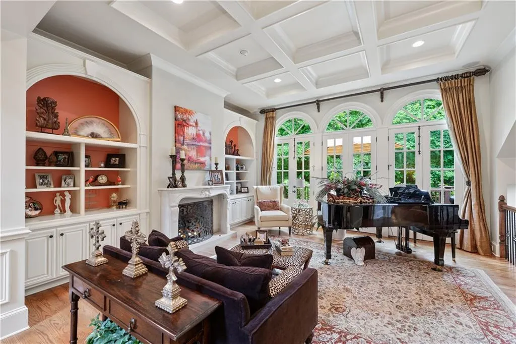 Living area with a high end fireplace, light wood-style flooring, healthy amount of natural light, coffered ceiling, and beamed ceiling