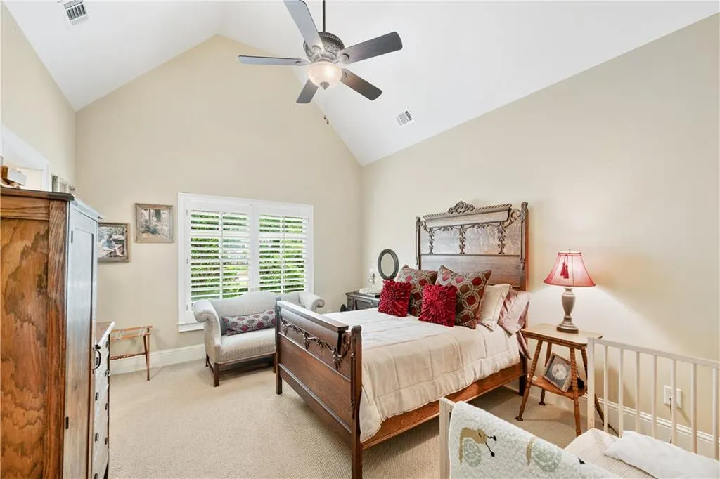 Carpeted bedroom featuring high vaulted ceiling and a ceiling fan