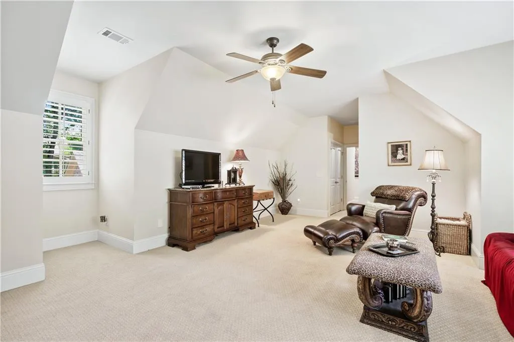 Living room with light carpet, ceiling fan, and lofted ceiling