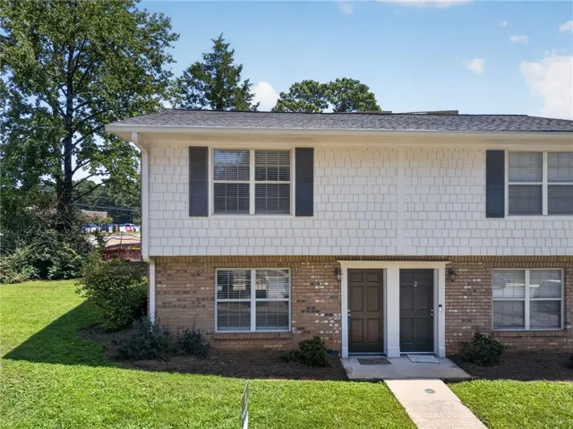 Brick and shake siding exterior with dark shutters, dual entry doors, and a concrete walkway