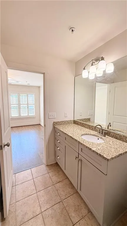 Bathroom vanity with a granite countertop, undermount sink, and brushed nickel faucet