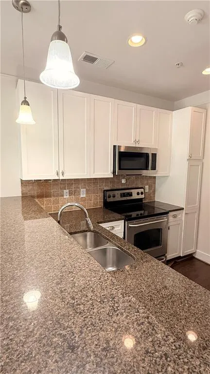 Kitchen with light-colored cabinetry, stainless steel appliances, a double basin sink, and pendant lighting