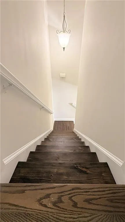 Staircase featuring dark wood-finish treads, white risers, and white baseboards