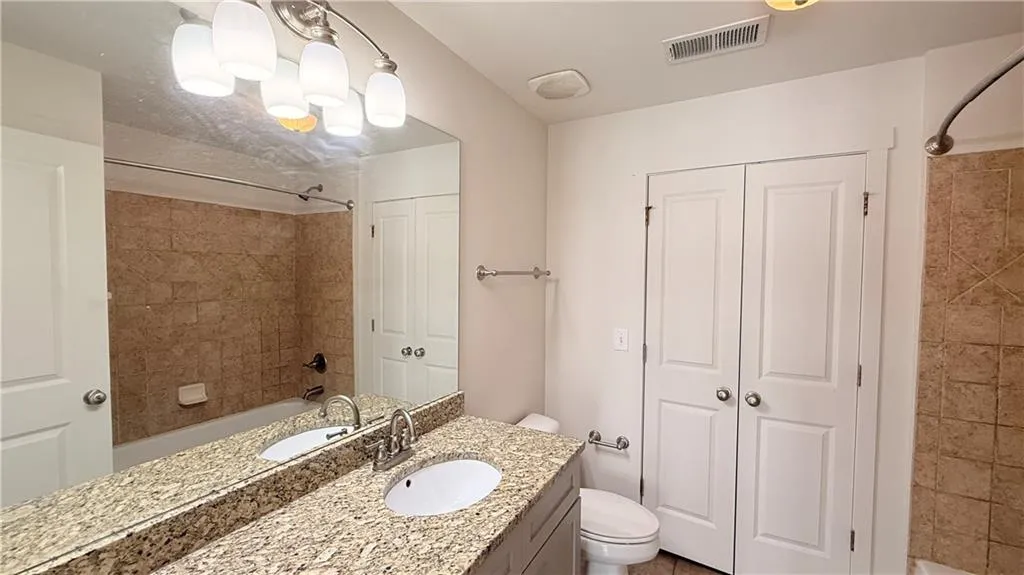 Dual vanity with integrated sinks, granite-finish countertop, and a large mirror