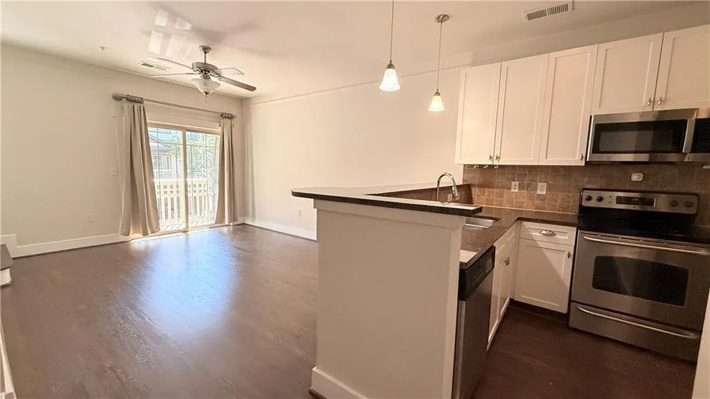 Open-concept living area featuring wood-finish flooring, a ceiling fan, and sliding glass doors