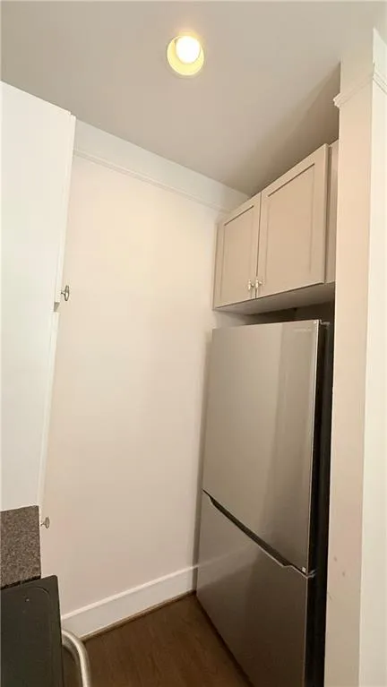 Recessed ceiling light, crown molding, stainless steel refrigerator, upper cabinetry, wood-finish flooring