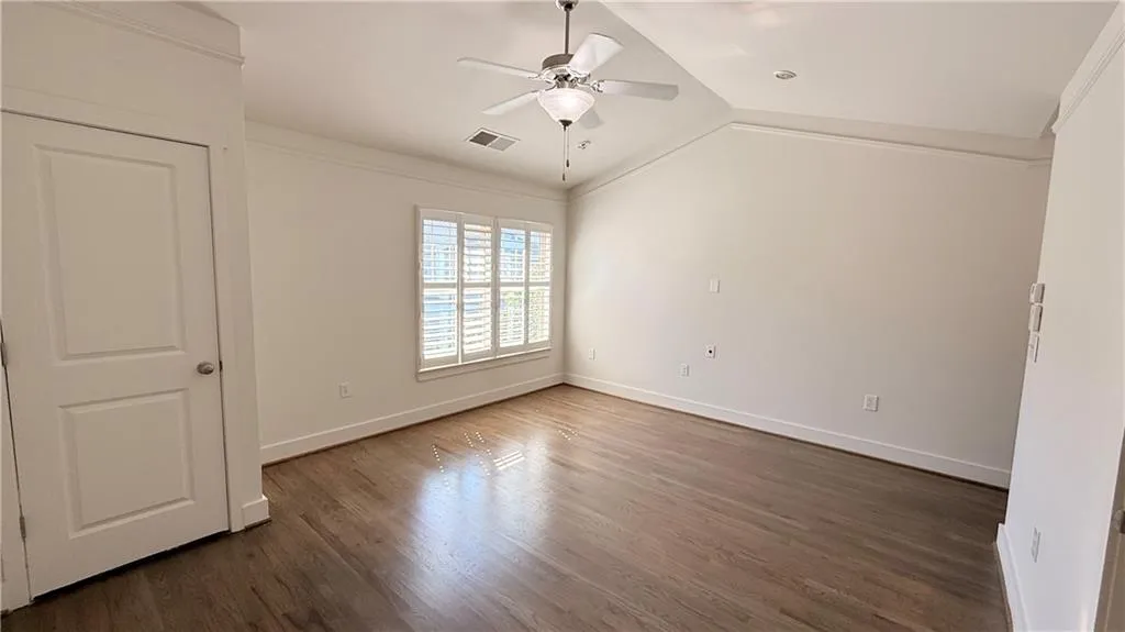 Vaulted ceiling with crown molding, wood-finish flooring, ceiling fan, recessed lighting, and plantation shutters