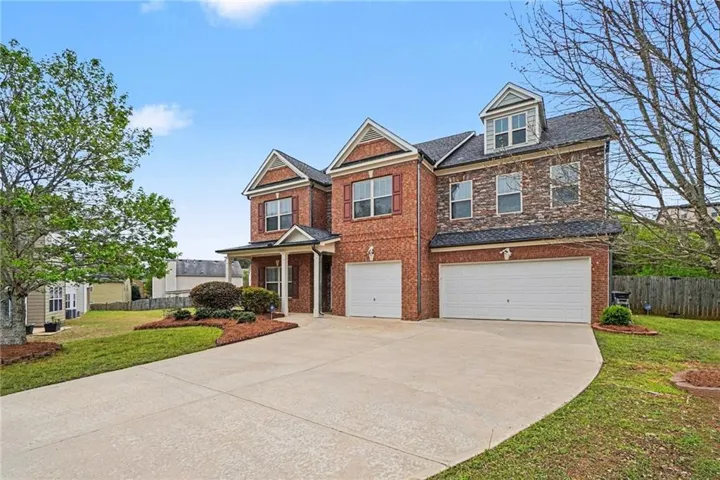 View of front facade with an attached garage, driveway, and brick siding