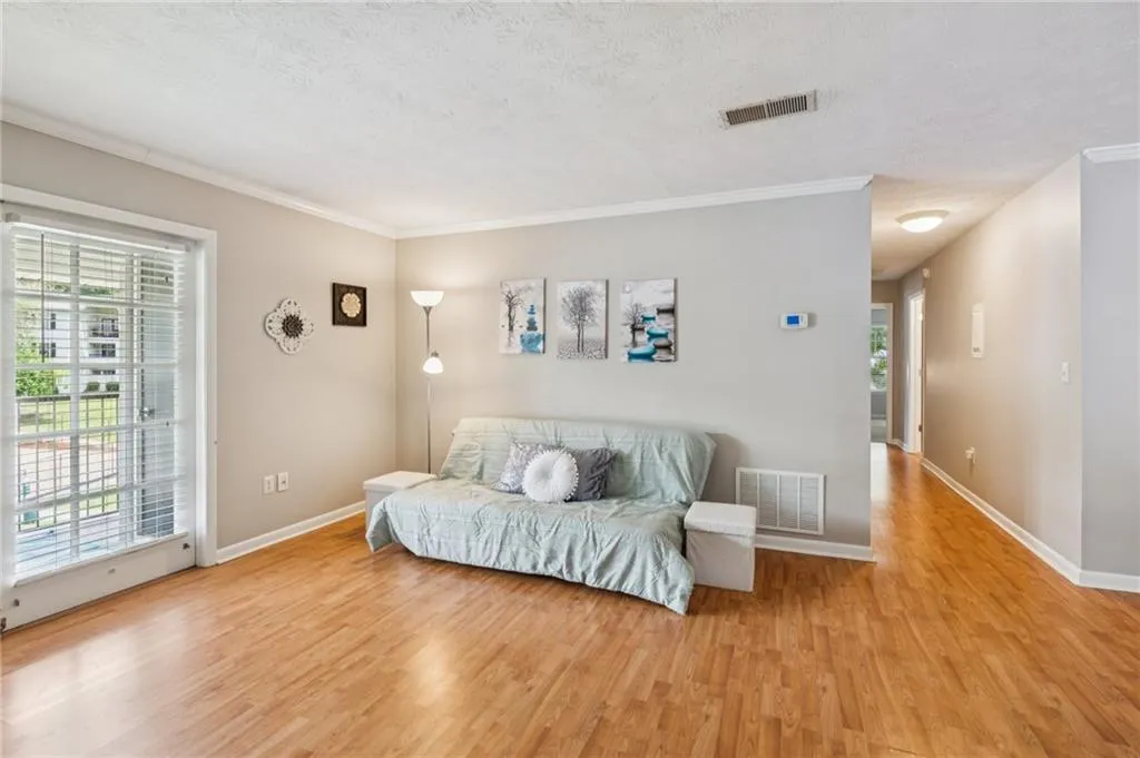 Living area with crown molding, wood finished floors, and a textured ceiling