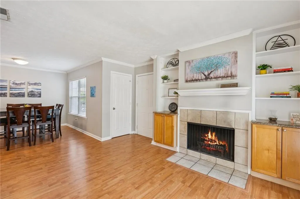 Living room with a fireplace, light wood-style flooring, ornamental molding, and built in features