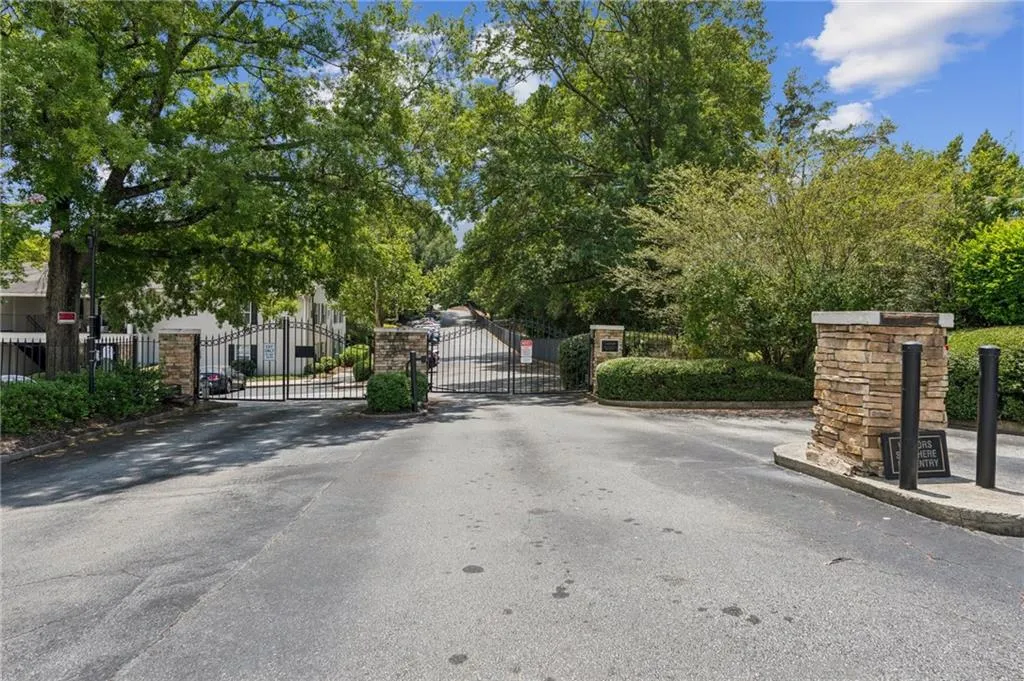 View of asphalt street featuring a gate, a gated entry, and curbs