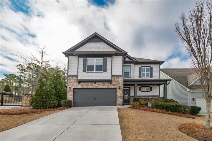 Craftsman inspired home with a garage, driveway, stone siding, and covered porch