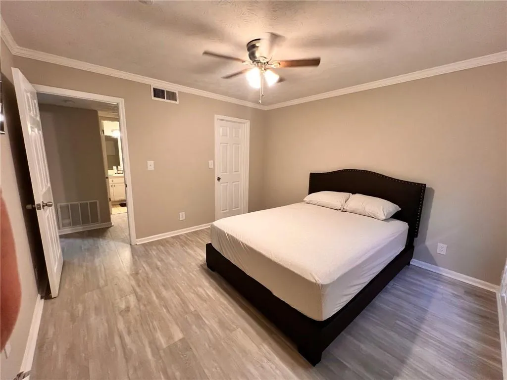 Bedroom featuring light wood-type flooring, crown molding, a textured ceiling, and a ceiling fan