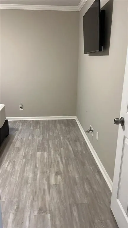 Laundry area featuring ornamental molding and light wood-style flooring