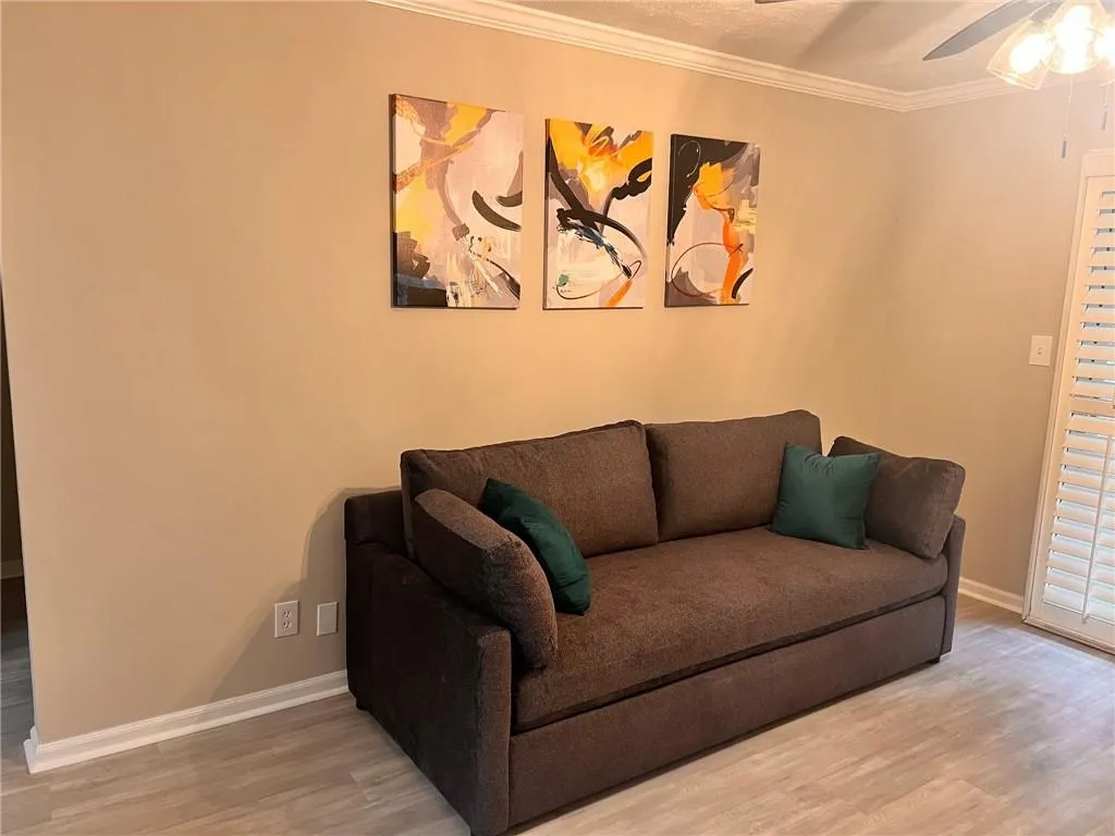 Living room with ornamental molding, a ceiling fan, wood finished floors, and a textured ceiling