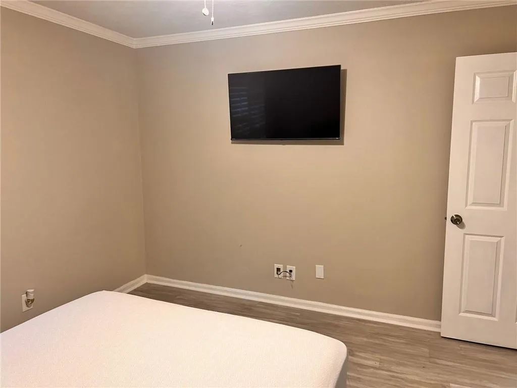 Bedroom with ornamental molding and wood finished floors
