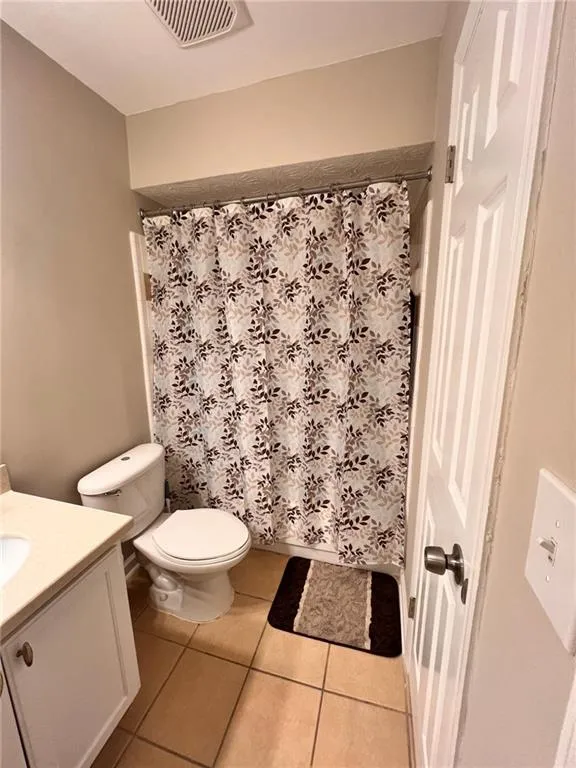 Full bath with vanity, light tile patterned floors, and curtained shower