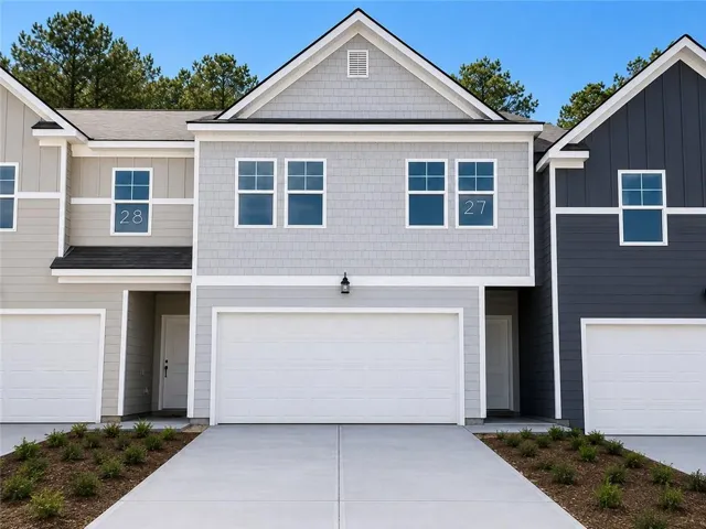 Modern townhome exterior with mixed siding, a prominent gable roof, and an attached two-car garage