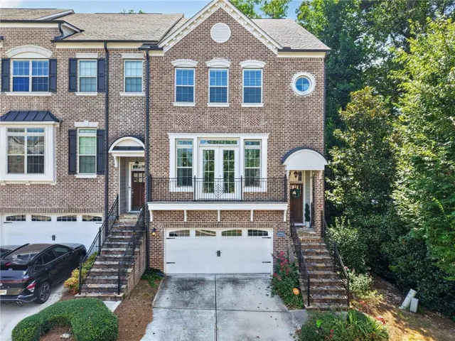 Brick exterior with multiple windows, arched entryway, and a balcony with wrought iron railing