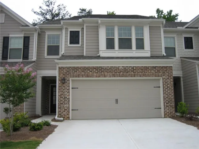 Brick and siding exterior with a two-car garage, concrete driveway, and an entryway with a dark-paneled door