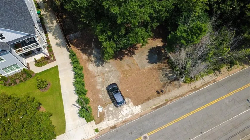 Expansive vacant lot featuring an existing partial concrete pad, mature perimeter trees, and street frontage