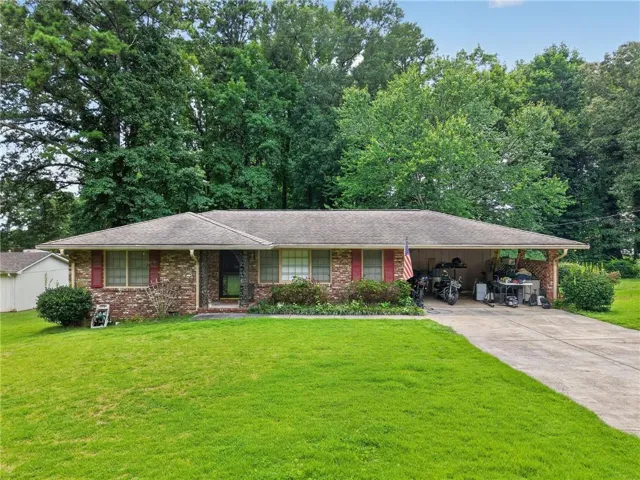 Brick exterior with red shutters, a covered carport, and a concrete driveway