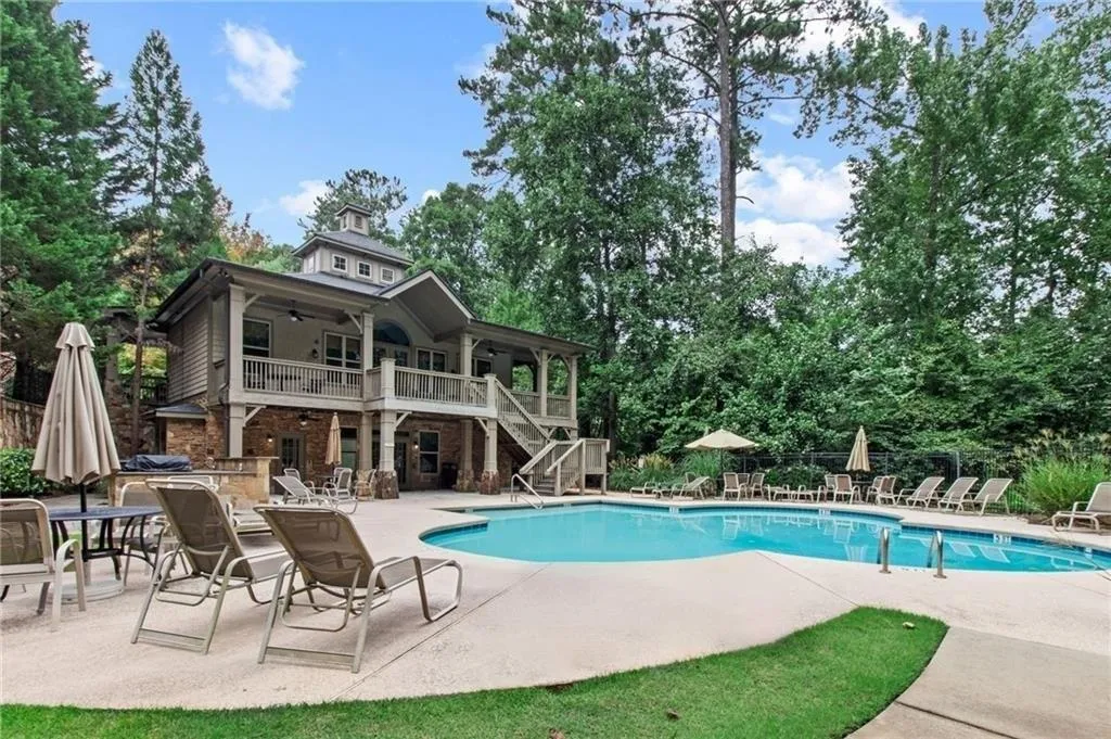 Community pool with a patio area, a ceiling fan, stairs, and view of wooded area