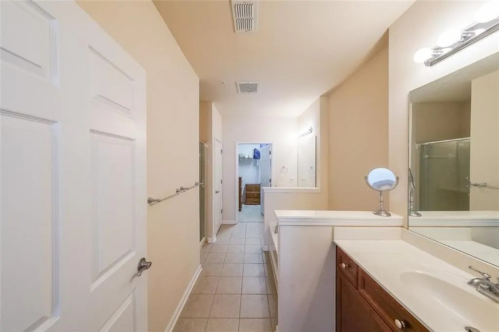 Bathroom featuring a shower stall, vanity, and light tile patterned flooring