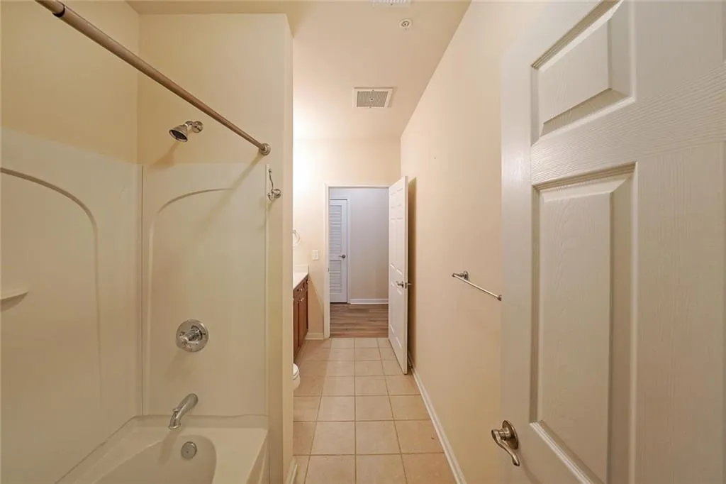 Bathroom with light tile patterned floors, tub / shower combination, and vanity