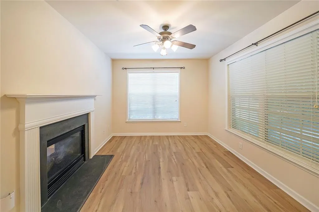 Unfurnished living room featuring light wood-type flooring, a glass covered fireplace, and ceiling fan