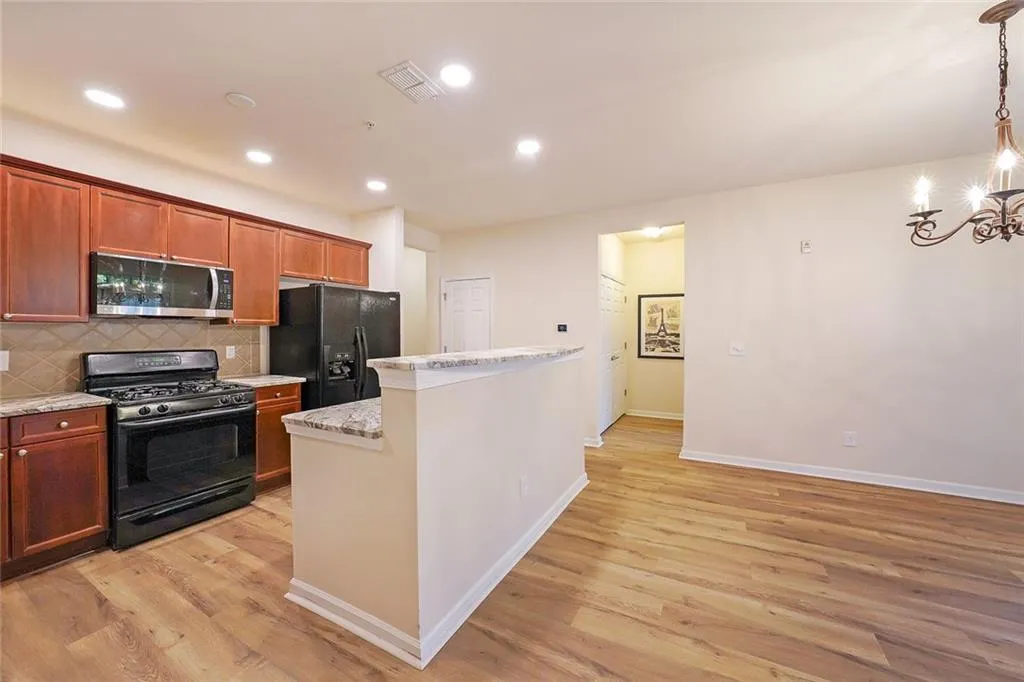 Kitchen with black appliances, backsplash, recessed lighting, a chandelier, and brown cabinets