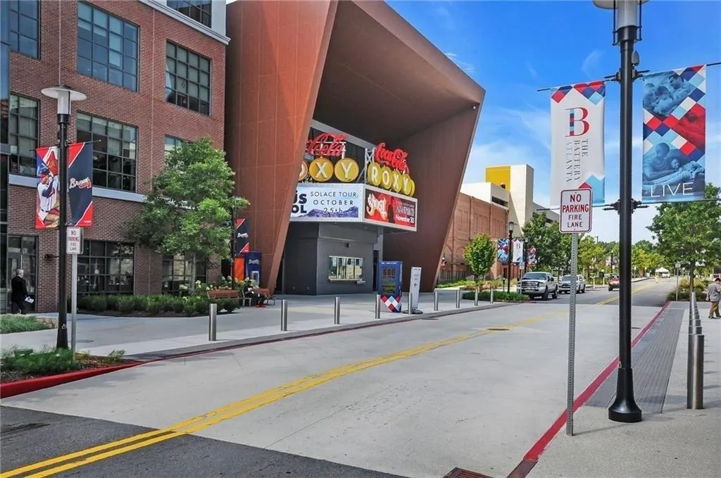 View of asphalt road featuring sidewalks, traffic signs, curbs, and street lights