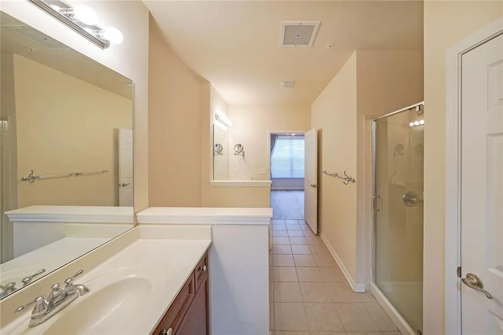 Full bath with light tile patterned flooring, a shower stall, and vanity