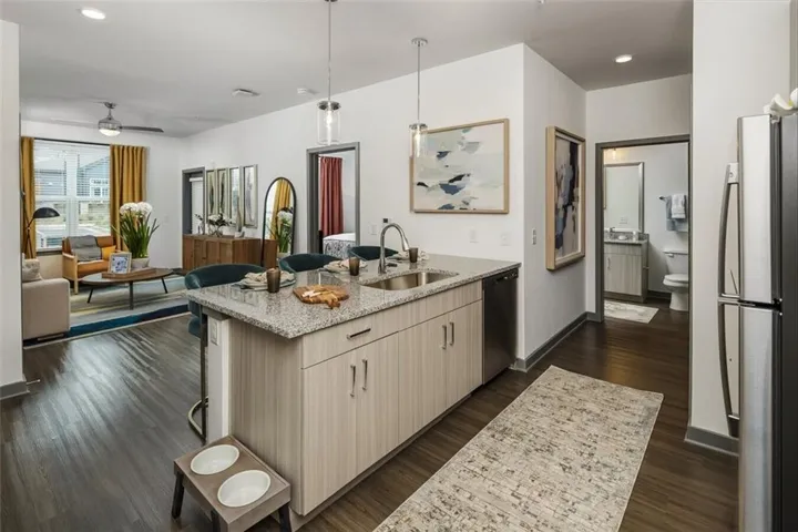 Kitchen with a breakfast bar area, freestanding refrigerator, light stone counters, hanging light fixtures, and recessed lighting