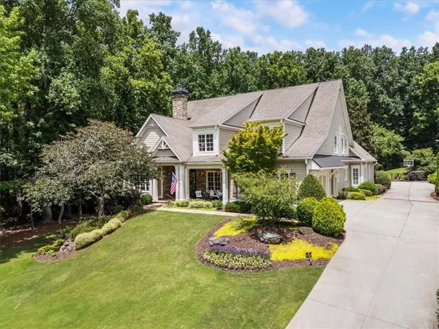 Craftsman-style residence featuring a prominent front porch, extensive landscaping, and a multi-car driveway