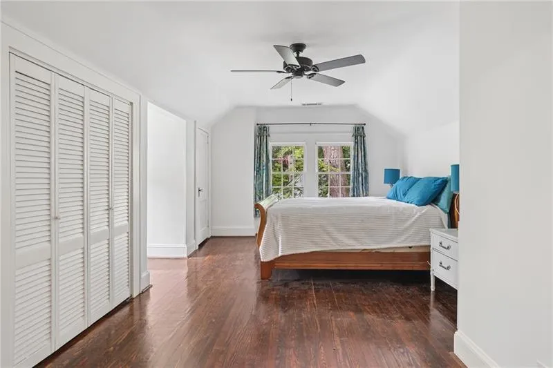 Hardwood flooring, slatted bi-fold closet doors, ceiling fan with light, and twin windows