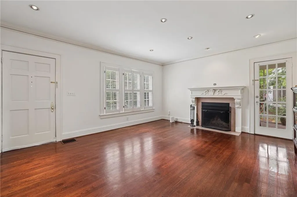 Hardwood flooring, recessed lighting, decorative fireplace with mantel, French door, and window shutters