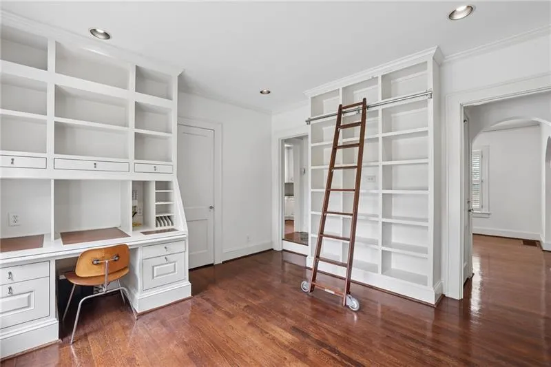 Built-in shelving units, integrated desk space, wood-finish flooring, recessed lighting, and arched doorways