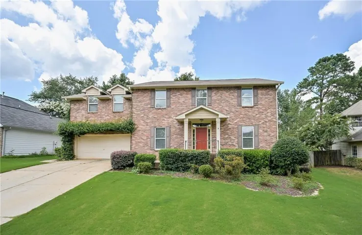 Brick two-story residence featuring a covered front entry with a red door