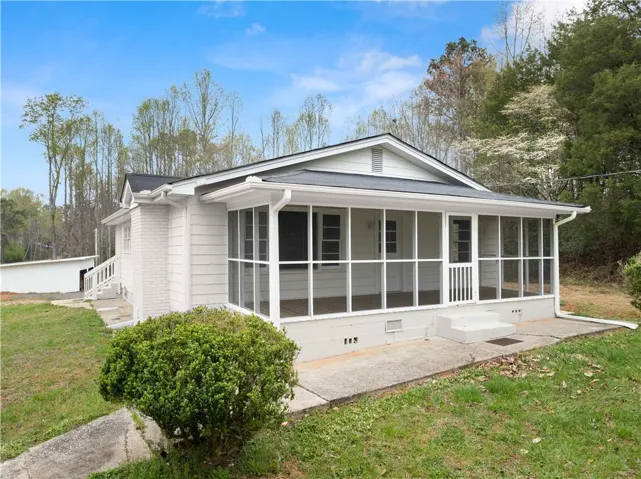 View of property exterior featuring a lawn, a sunroom, and entry steps