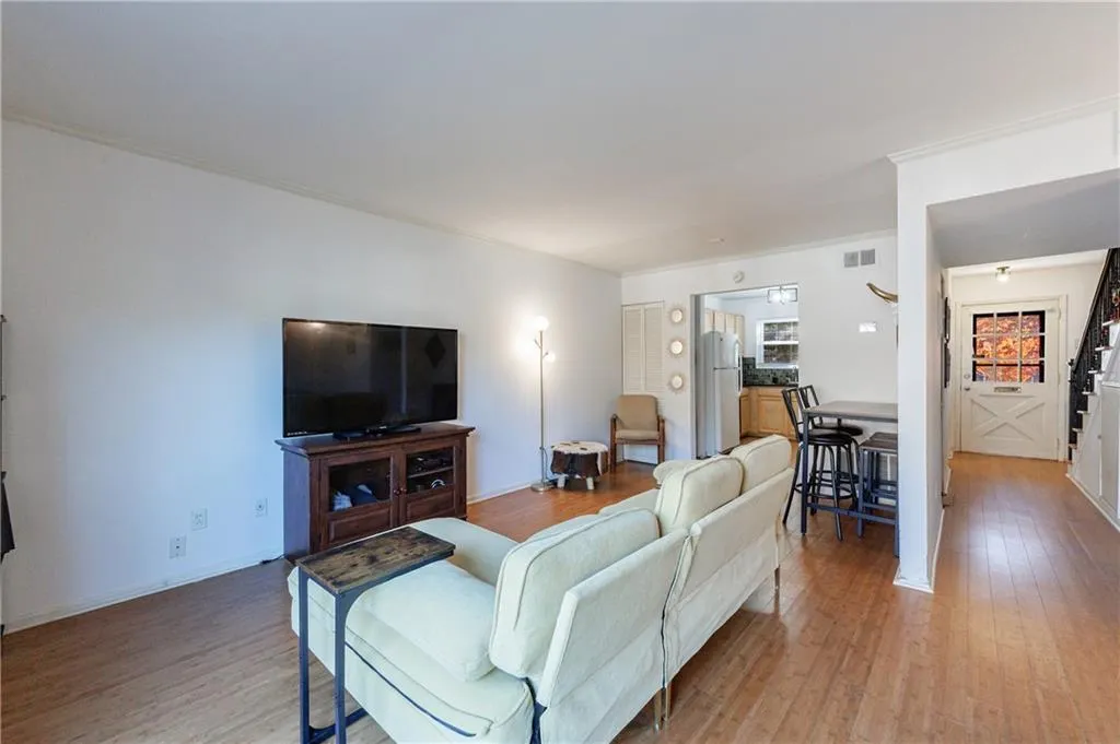Living area featuring light wood-style flooring, ornamental molding, and stairway
