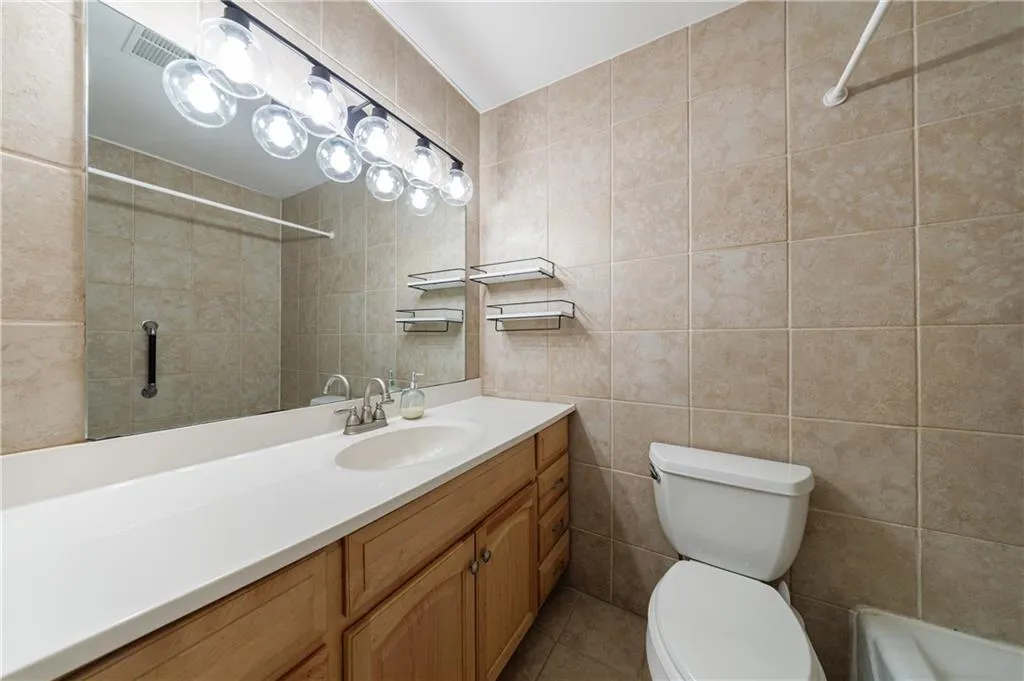 Bathroom featuring tile walls, vanity, and a shower